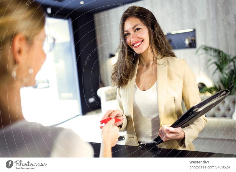 Lächelnde Geschäftsfrau überreicht Kreditkarte am Empfang Leute Menschen People Person Personen Kunden Kundschaft Job Berufe Berufstätigkeit Beschäftigung Jobs