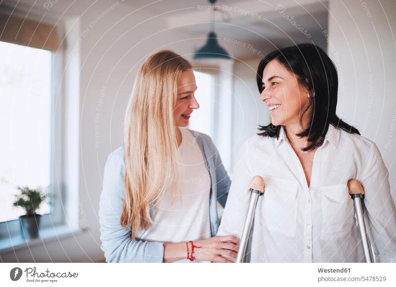 Tochter hilft ihrer Mutter beim Gehen mit Krücken Europäer junge Frau 20-25 Jahre reife Frau 55-60 Jahre Zuhause Slowakei Innenaufnahme zwei Personen