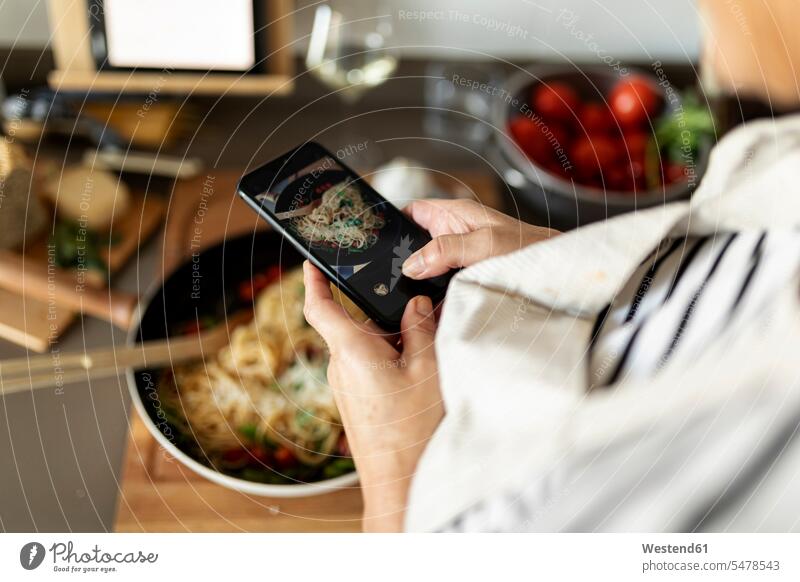 Nahaufnahme einer Frau, die ein Smartphone-Foto von ihrem Nudelgericht in der heimischen Küche macht Leute Menschen People Person Personen Alleinstehende