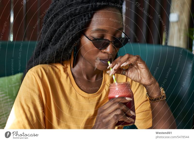 Junge Frau mit Dreadlocks trinkt einen Smoothie in einem Café Schwarzer Afrikanisch Farbige Afrikanische Abstammung dunkelhäutig Farbiger Gesundheitsbewusstsein