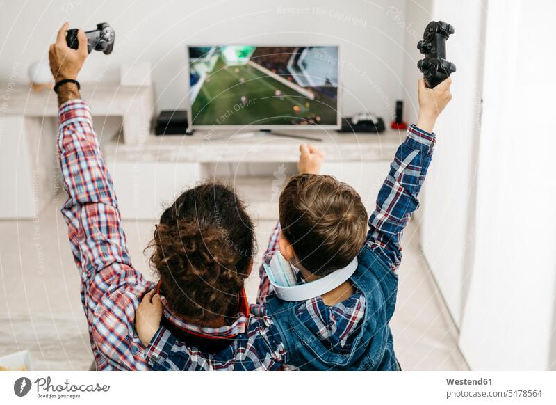 Vater und Sohn spielen Computerspiel zu Hause Computerspiele Zuhause daheim Vater und Söhne Väter und Söhne Arm umlegen Arme umlegen Papas Vati Vatis Papis