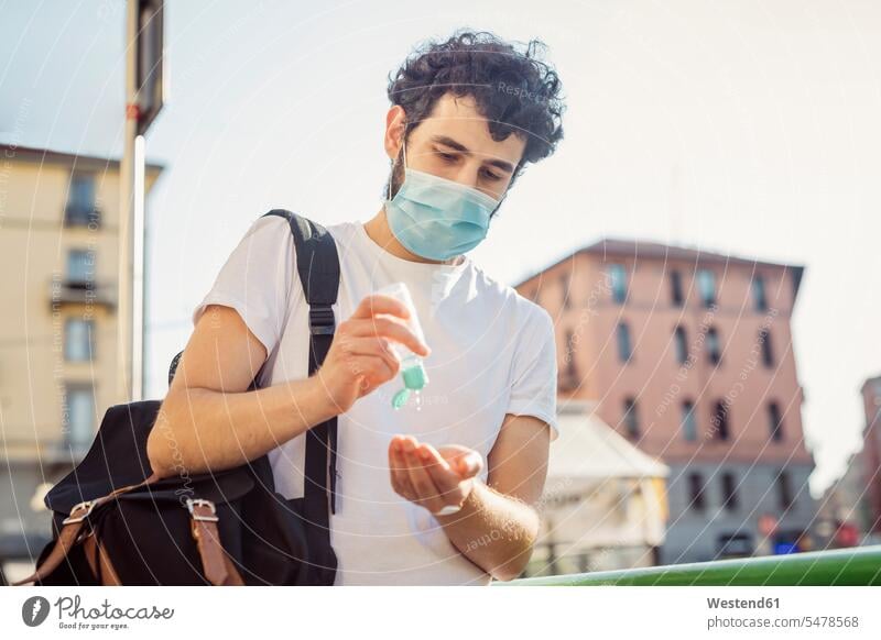 Mann mit Gesichtsmaske wäscht sich die Hände mit Desinfektionsmittel, während er gegen den klaren Himmel steht Farbaufnahme Farbe Farbfoto Farbphoto