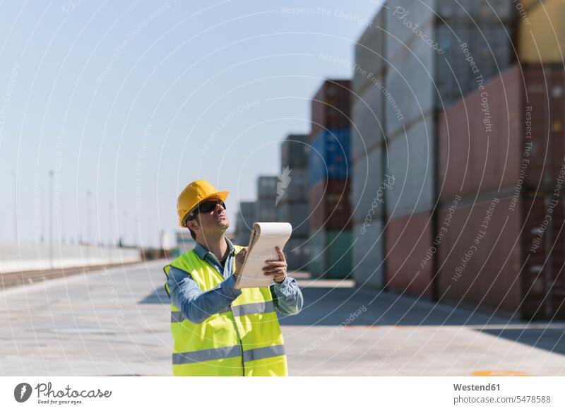 Arbeiter mit einem Notizblock in der Nähe von Frachtcontainern auf einem Industriegelände Hafengebiet Hafengebiete Beruf Berufstätigkeit Berufe Beschäftigung