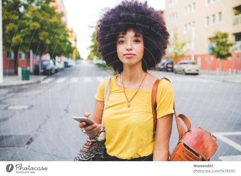Porträt einer selbstbewussten jungen Frau mit Afrofrisur in der Stadt Leute Menschen People Person Personen gelockt gelockte Haare gelocktes Haar lockig