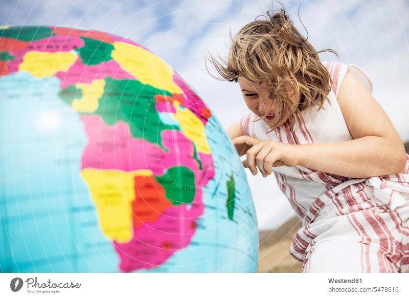 Kleines Mädchen, das auf einen aufblasbaren Globus zeigt Erdkugel Globen Weltkugel entdecken freuen Glück glücklich sein glücklichsein zufrieden Global
