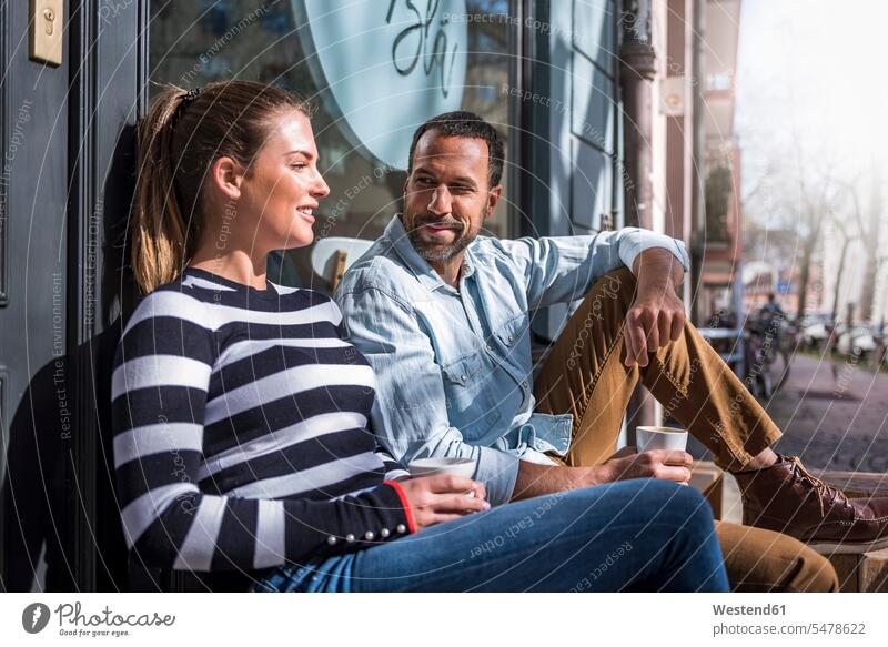 Mann und Frau sitzen vor einem Café und unterhalten sich Cafe Kaffeehaus Bistro Cafes Cafés Kaffeehäuser Paar Pärchen Paare Partnerschaft sprechen reden sitzend