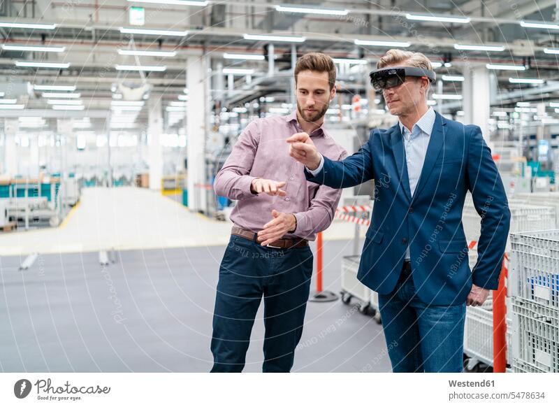 Zwei Geschäftsleute mit AR-Brillen in einer modernen Fabrik Arbeitskollege Arbeitskollegen Kollege Partner Partnerschaften Job Berufe Berufstätigkeit