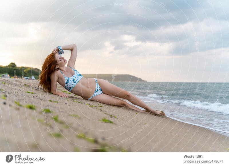 Junge Frau am Strand liegend Badebekleidung Bikinis sommerlich Sommerzeit entspannen relaxen entspanntheit relaxt geniessen Genuss liegt Muße sinnlich alleine