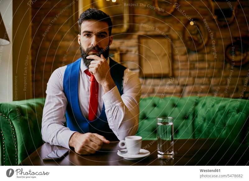 Porträt eines modischen jungen Mannes, der auf einer Couch in einem Cafe sitzt Portrait Porträts Portraits Männer männlich sitzen sitzend Kaffeehaus Bistro