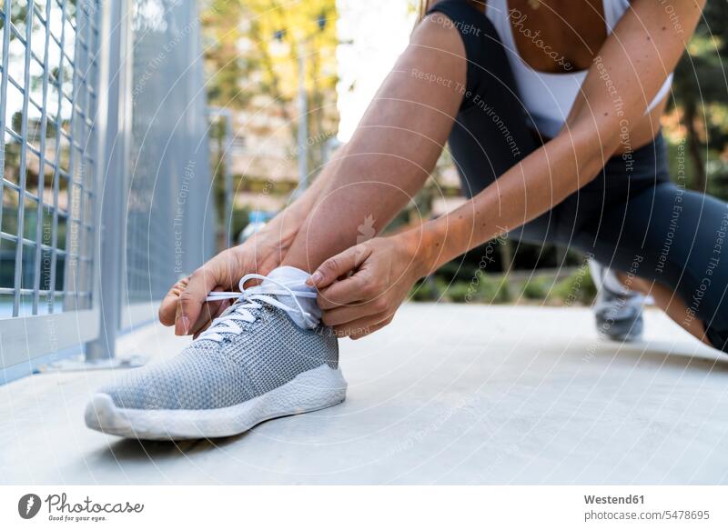 Nahaufnahme einer sportlichen Frau, die sich vor dem Training die Schuhe zubindet binden weiblich Frauen Sportplatz Sportplaetze Sportplätze Erwachsener