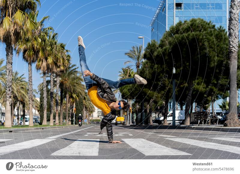 Spanien, Barcelona, Mann in der Stadt macht einen Handstand auf der Straße aufstützen aufgestuetzt aufgestützt verspielt spielerisch leicht mühelos Leichtigkeit