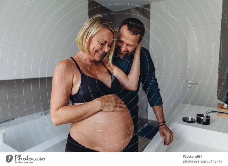 Glückliches reifes schwangeres Paar, das den Bauch der werdenden Mutter im Badezimmer beobachtet Schwangere schwangere Frau ansehen Bäuche Zimmer Raum Räume