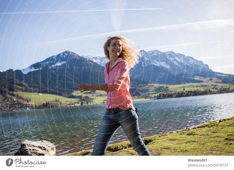 Österreich, Tirol, Walchsee, lächelnde Frau beim Spaziergang am See gehen gehend geht Seen weiblich Frauen Gewässer Wasser Erwachsener erwachsen Mensch Menschen