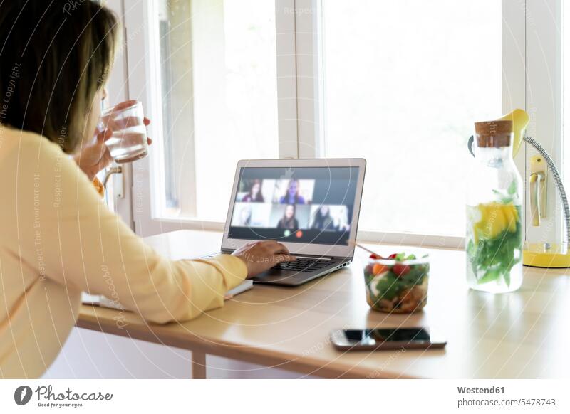 Junge berufstätige Frau bei Videokonferenz mit Kollegen über Laptop bei der Arbeit zu Hause Farbaufnahme Farbe Farbfoto Farbphoto Spanien Innenaufnahme