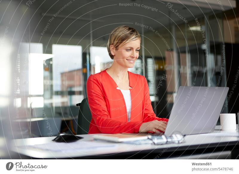Lächelnde Geschäftsfrau benutzt Laptop im Büro Job Berufe Berufstätigkeit Beschäftigung Jobs geschäftlich Geschäftsleben Geschäftswelt Geschäftsperson