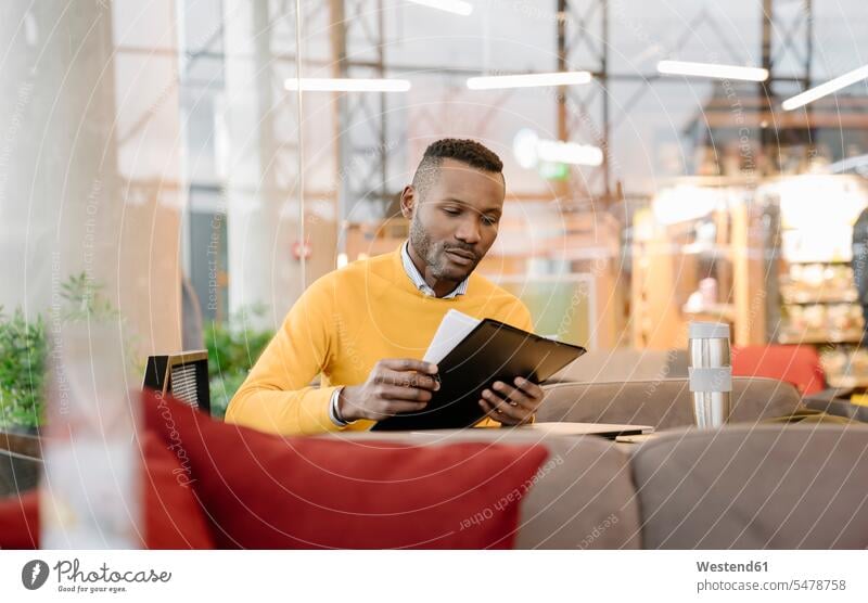 Mann mit wiederverwendbarem Becher beim Lesen von Dokumenten in einem Cafe Job Berufe Berufstätigkeit Beschäftigung Jobs geschäftlich Geschäftsleben