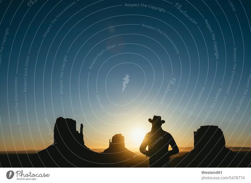USA, Utah, Monument Valley, Silhouette eines Mannes mit Cowboyhut bei Sonnenaufgang Cowboyhuete Cowboyhüte betrachten betrachtend Umriß Gegenlicht