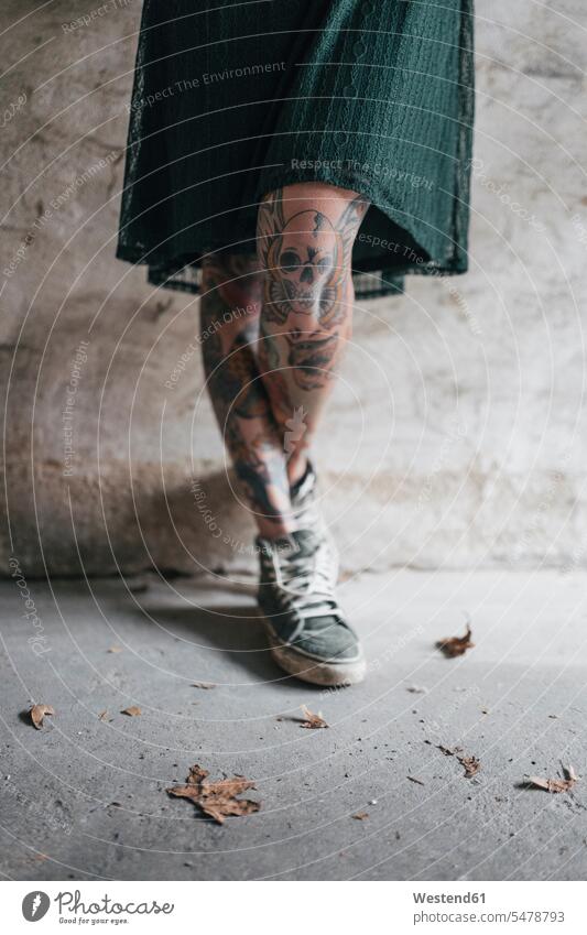 Beine einer jungen Frau mit Tätowierungen weiblich Frauen Kleid Kleider Mauer Mauern Tattoo Tatoos Taetowierung Tattoos Taetowierungen rebellisch Totenkopf