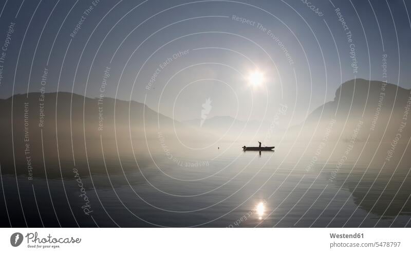 Österreich, Mondsee, Blick auf Fischerboot im See mit nebligem Morgen wolkenlos Textfreiraum ohne Wolken Spiegelung Spiegelungen Silhouette Umrisse Gegenlicht