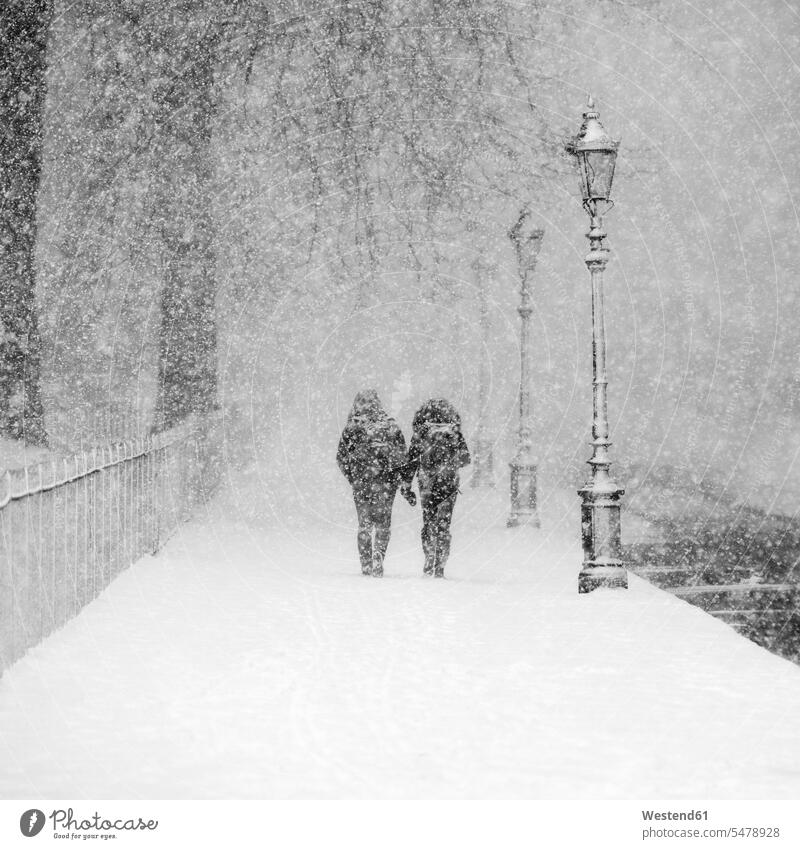 Paar zu Fuß zusammen in schneebedeckten Park während schweren Schneefall Außenaufnahme außen draußen im Freien Tag Tageslichtaufnahme Tageslichtaufnahmen