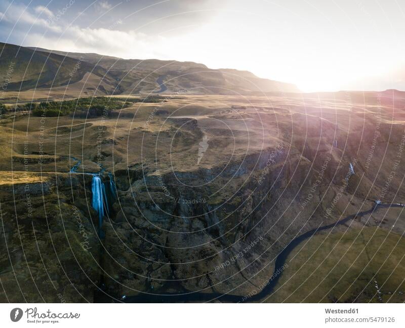 Island, Luftaufnahme eines Wasserfalls, der bei Sonnenuntergang über hohe Klippen plätschert Langzeitbelichtung Außenaufnahme außen draußen im Freien