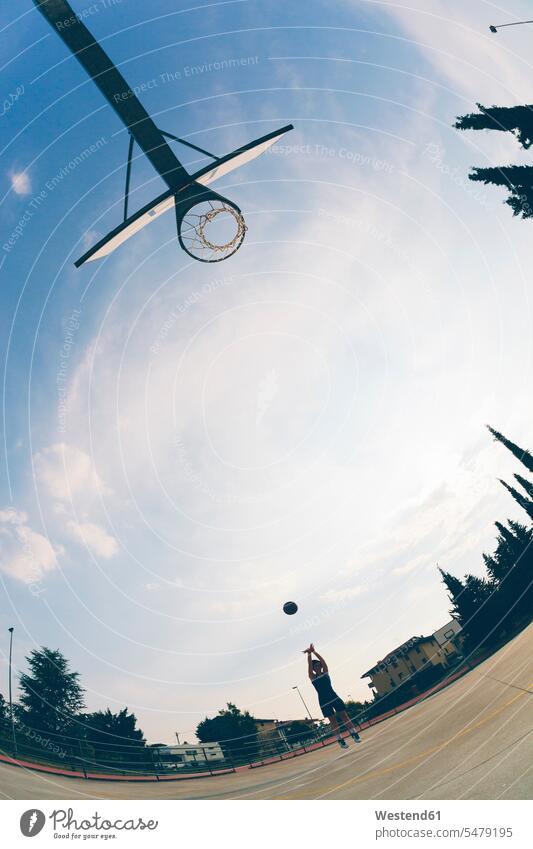 Fischaugenansicht eines Teenager-Mädchens, das Basketball gegen den Himmel spielt Farbaufnahme Farbe Farbfoto Farbphoto Außenaufnahme außen draußen im Freien
