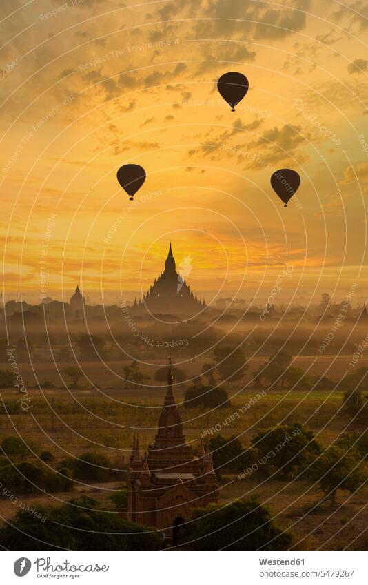 Myanmar, Region Mandalay, Bagan, Silhouetten von Heissluftballons, die in der nebligen Morgendämmerung über alte Tempel fliegen Außenaufnahme außen draußen