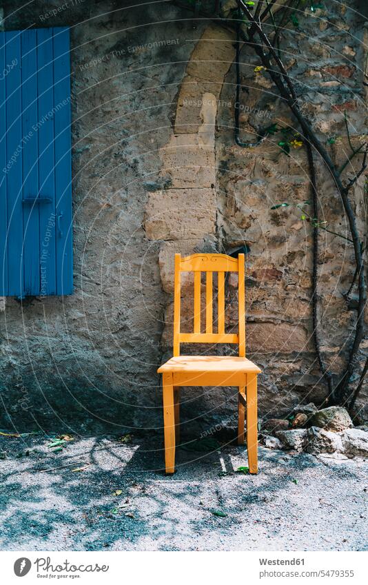 Frankreich, Grignan, gelber Holzstuhl vor einem alten Haus Niemand leer leere Hausfassade Fassade Einzelner Gegenstand 1 Einzelgegenstand ein Gegenstand einzeln