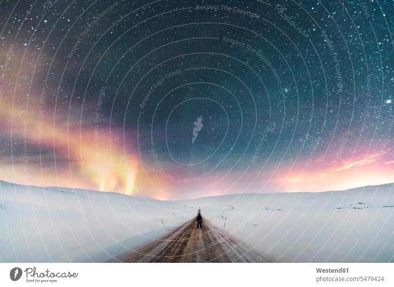 Mann steht auf Landstraße unter Sternenhimmel mit Nordlicht, Lebesby, Norwegen Touristen nachts Jahreszeiten winterlich Winterzeit stehend Kälte Abenteuer