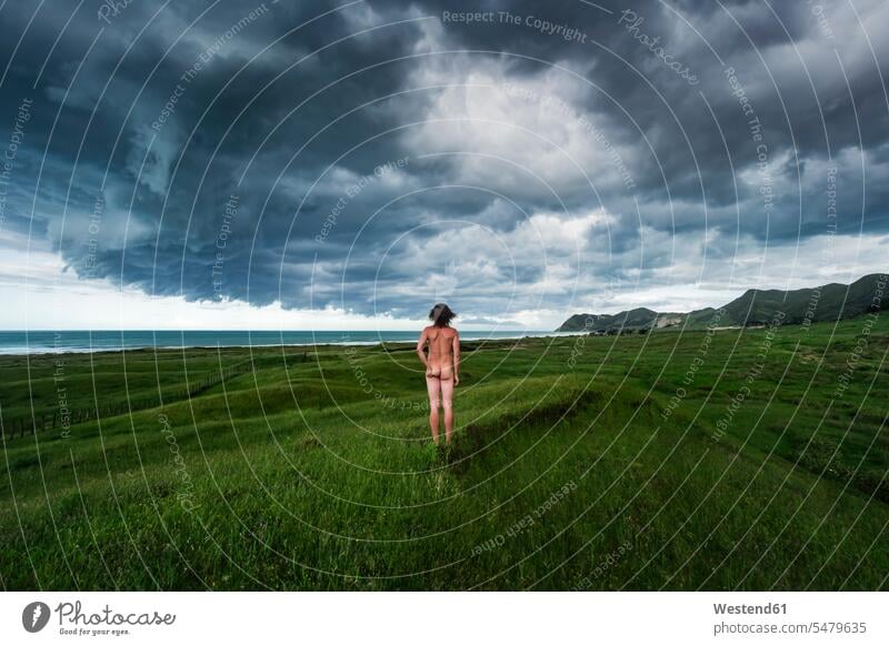 Neuseeland, Nordinsel, Rückansicht eines nackten Mannes mit Blick auf eine Gewitterwolke über blauem Meer Gisborne District East Cape Ost-Kap Fernweh Reiselust
