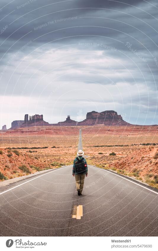 USA, Utah, Mann mit Rucksack zu Fuß auf der Straße zum Monument Valley Rucksäcke junger Mann junge Männer Strassen Straßen stehen stehend steht gehen gehend