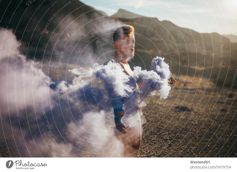 Nackter Mann mit Rauchbombe steht bei Sonnenschein in der Wüste Farbaufnahme Farbe Farbfoto Farbphoto Spanien Freizeitbeschäftigung Muße Zeit Zeit haben