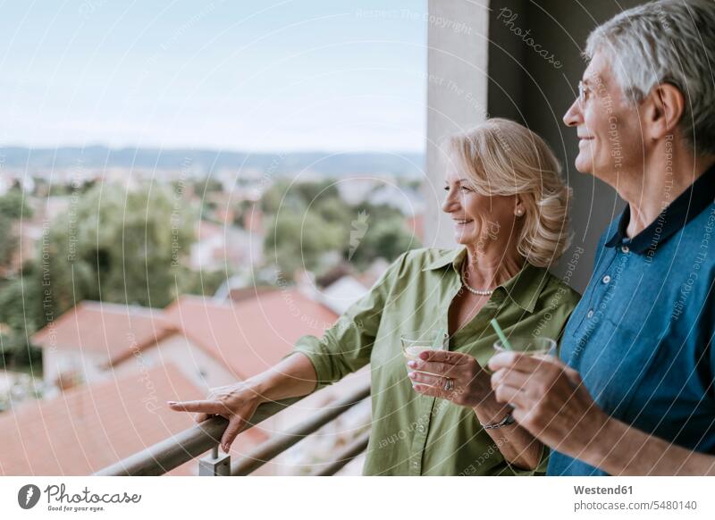 Lächelndes älteres Paar auf dem Balkon mit Blick auf die Aussicht Pärchen Paare Partnerschaft Senior ältere Männer älterer Mann Senioren lächeln Balkone Mensch