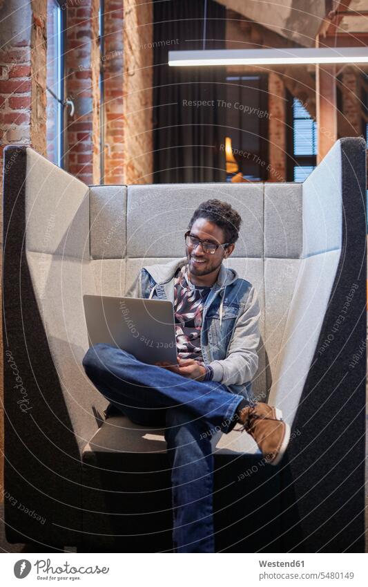 Junger Mann arbeitet in einem kreativen Start-up-Unternehmen und benutzt einen Laptop junger Mann junge Männer Firma Notebook Laptops Notebooks Kreative
