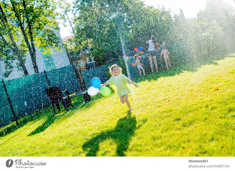 Kleines Mädchen amüsiert sich mit Rasensprenger im Garten weiblich Kind Kinder Kids Mensch Menschen Leute People Personen spielen laufen rennen Gärten Gaerten