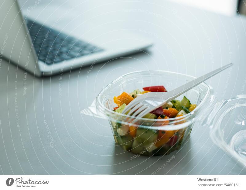 Plastikschüssel mit Salat auf Schreibtisch im Büro Plastikschale Schale Plastikschalen Business Geschäftsleben Geschäftswelt geschäftlich Plastikgabel
