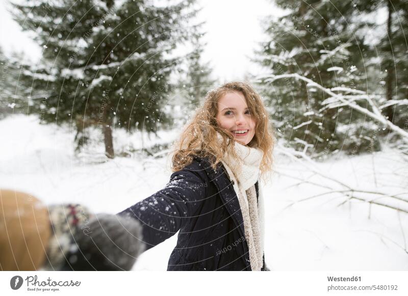 Porträt einer glücklichen jungen Frau, die im Winterwald die Hand hält weiblich Frauen Winterlandschaft Winterlandschaften Portrait Porträts Portraits