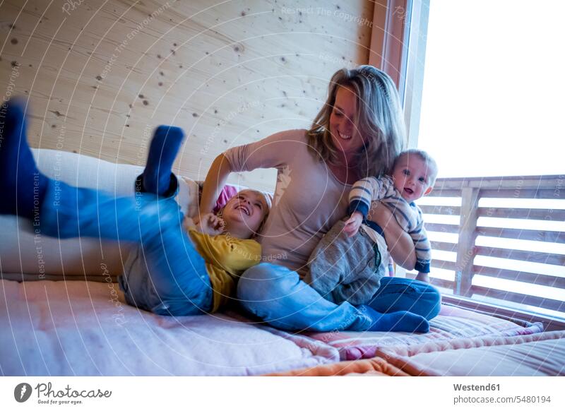 Mutter spielt mit ihren kleinen Söhnen zu Hause Zufriedenheit zufrieden Freizeitkleidung casual Freizeitbekleidung Muße Kindheit Wohnzimmer Wohnraum Wohnung