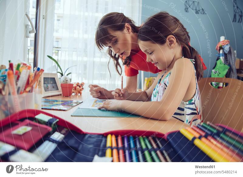 Mutter hilft Mädchen, ihre Schularbeiten zu Hause zu erledigen lernen Tochter Hausaufgaben Kind Familie Mensch Eltern Kommunikation Freizeitkleidung