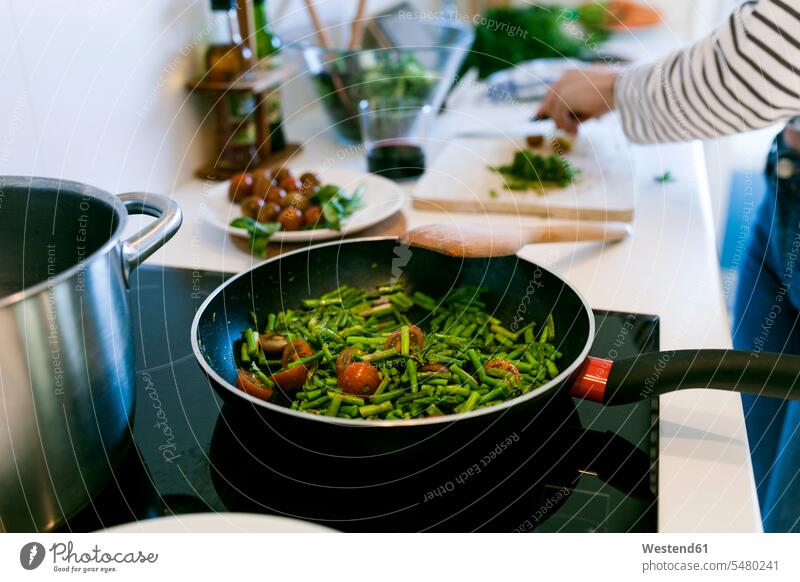 Junge Frau kocht in ihrer Küche vegane Pasta weiblich Frauen Tomate Speisetomaten Tomaten Zuhause zu Hause daheim kochen vegetarisch Vegetarische Nahrung