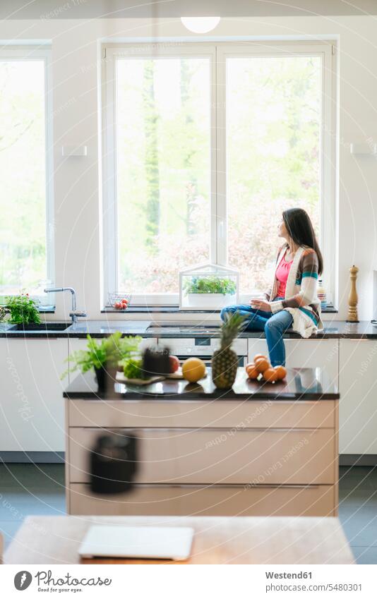 Frau in der Küche, die aus dem Fenster schaut entspannt entspanntheit relaxt ernst Ernst Ernsthaftigkeit ernsthaft weiblich Frauen sitzen sitzend sitzt