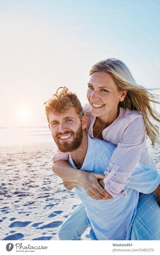 Porträt eines glücklichen Paares am Strand lächeln Glück glücklich sein glücklichsein Huckepack Beach Straende Strände Beaches Pärchen Partnerschaft Mensch
