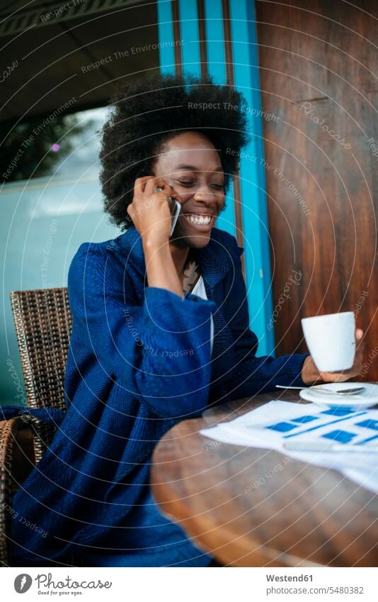 Porträt einer jungen Frau, die beim Kaffeetrinken in einem Straßencafé mit dem Handy telefoniert Schwarzer Afrikanisch Farbige Afrikanische Abstammung