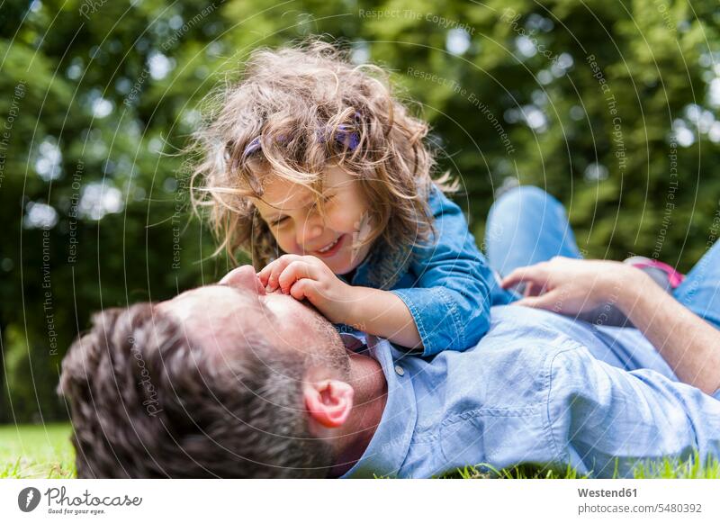 Vater kuschelt mit Tochter auf der Wiese im Park Papas Väter Vati Vatis Papis liegen liegend liegt Töchter Eltern Familie Familien Mensch Menschen Leute People