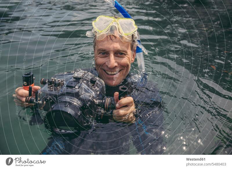 Porträt eines glücklichen Mannes mit Unterwasser-DSLR-Kamerakoffer in einem See Fotoapparat Fotokamera lachen Taucher Kameras Männer männlich tauchen positiv