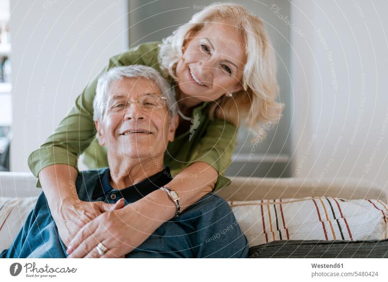Porträt eines liebevollen älteren Ehepaares zu Hause Senior ältere Männer älterer Mann Senioren lächeln Sofa Couches Liege Sofas Paar Pärchen Paare
