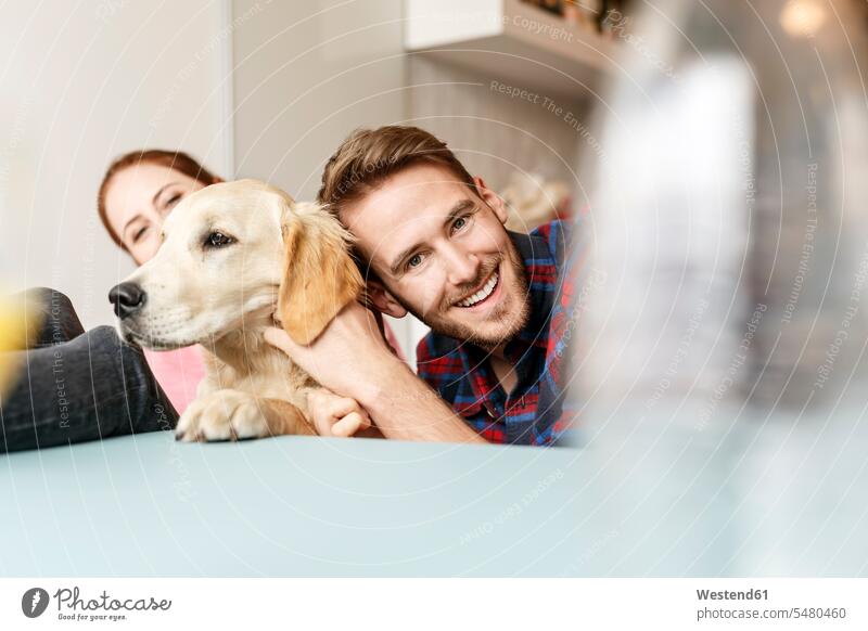 Glückliches junges Paar mit Hund zu Hause Hunde Zuhause daheim glücklich glücklich sein glücklichsein spielen Pärchen Paare Partnerschaft Haustier Haustiere