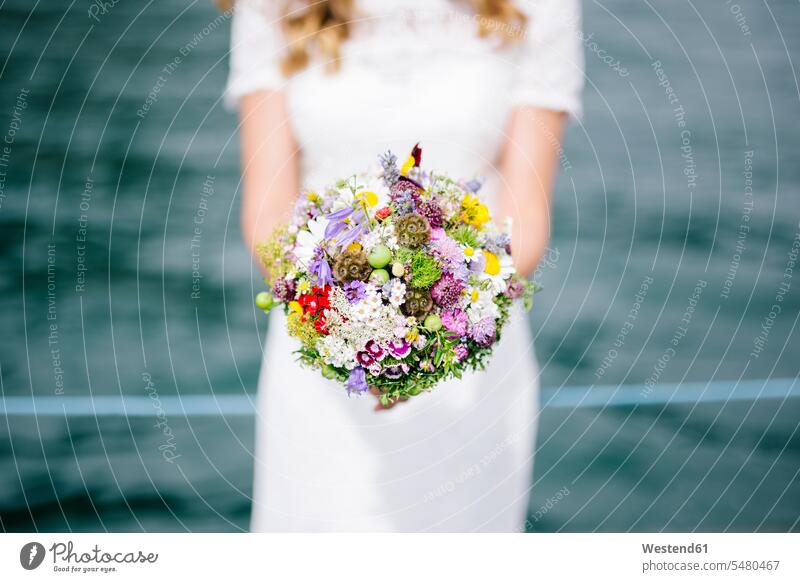 Braut hält ihren Brautstrauss Außenaufnahme draußen im Freien Frau weiblich Frauen Österreich bunt farbig mehrfarbig Blumenstrauß Bouquet Blumenstrauss