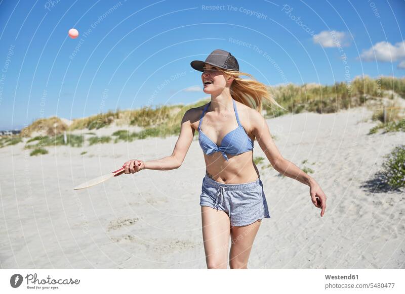 Glückliche junge Frau am Strand beim Strandpaddeln Urlaub Ferien lachen Beach Straende Strände Beaches weiblich Frauen Reise Travel positiv Emotion Gefühl