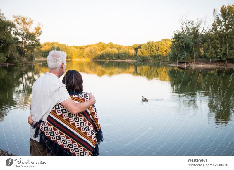 Älteres Ehepaar an einem See beim Entenschauen Senior ältere Männer älterer Mann Senioren umarmen Umarmung Umarmungen Arm umlegen Seen Paar Pärchen Paare